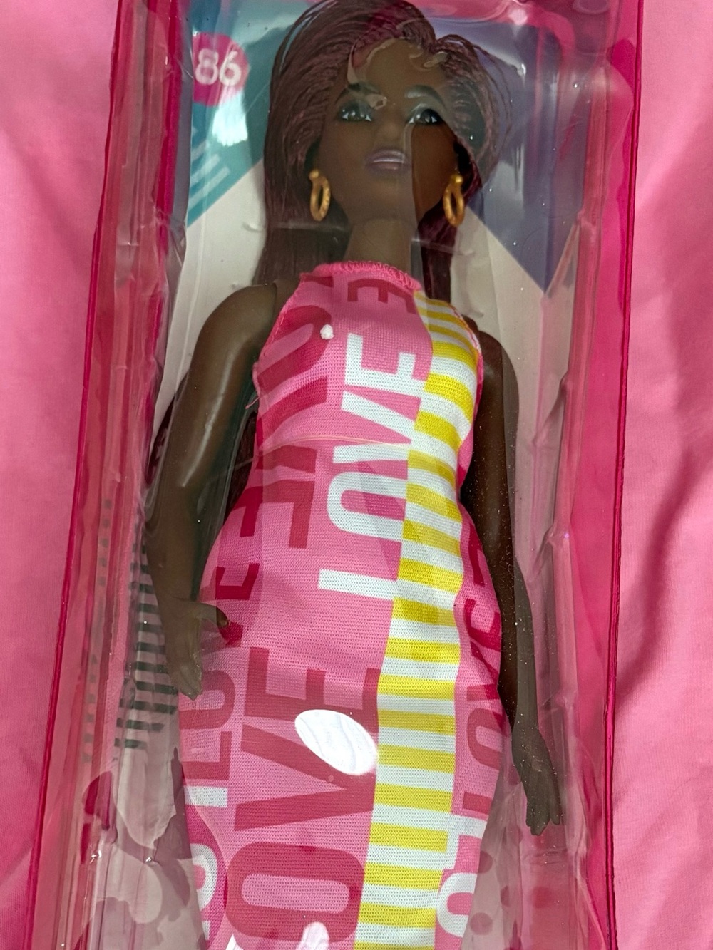 Black Barbie with a pink dress on with the words love going down the front